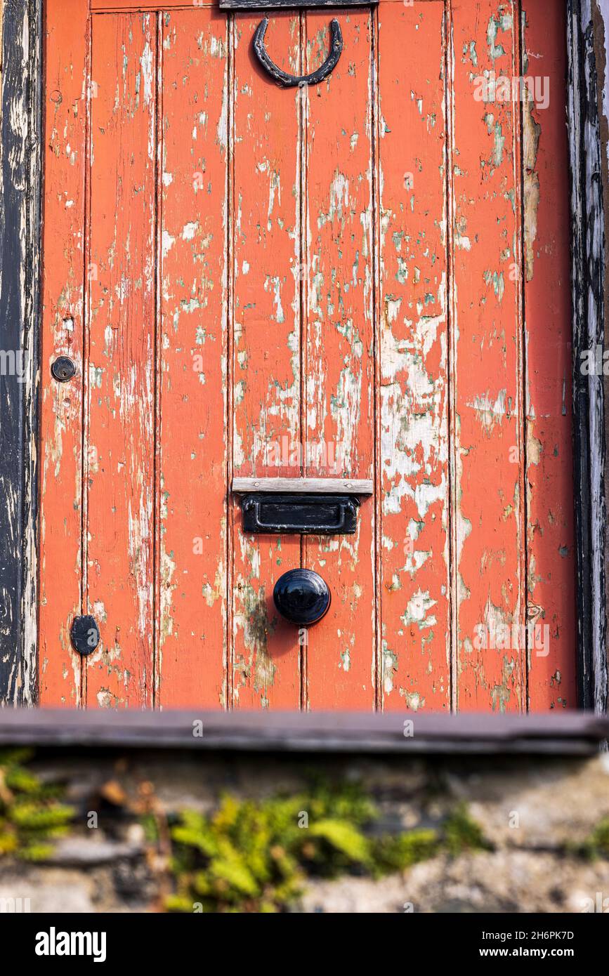 Peeling red paint on a cottage front door near Llanberis, Snowdonia, Wales, UK, Stock Photo