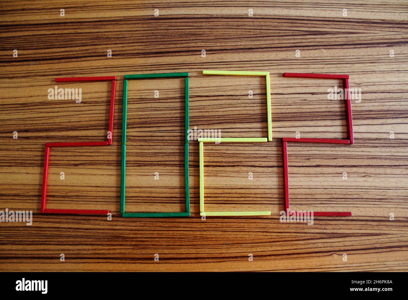 Bunte Holzstäbchen in rot, grün und gelb, auf einem Holztisch liegend, die die Zahl 2022 darstellen. Stock Photo