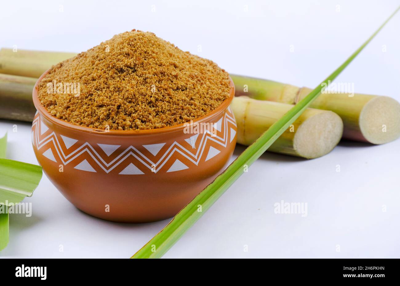 Jaggery powder and sugarcane isolated on white background. Jaggery is ...