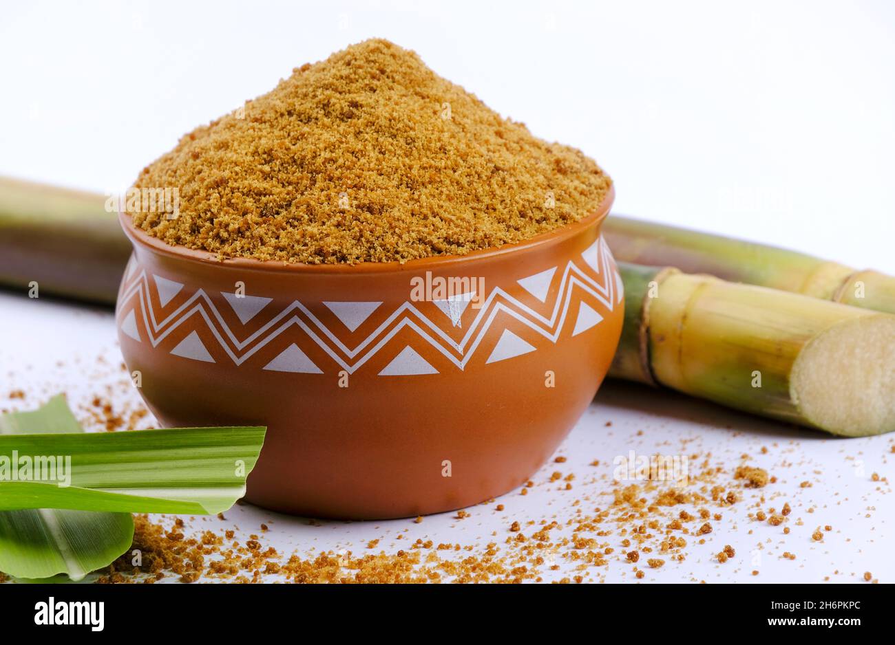 Jaggery powder and sugarcane isolated on white background. Jaggery is ...