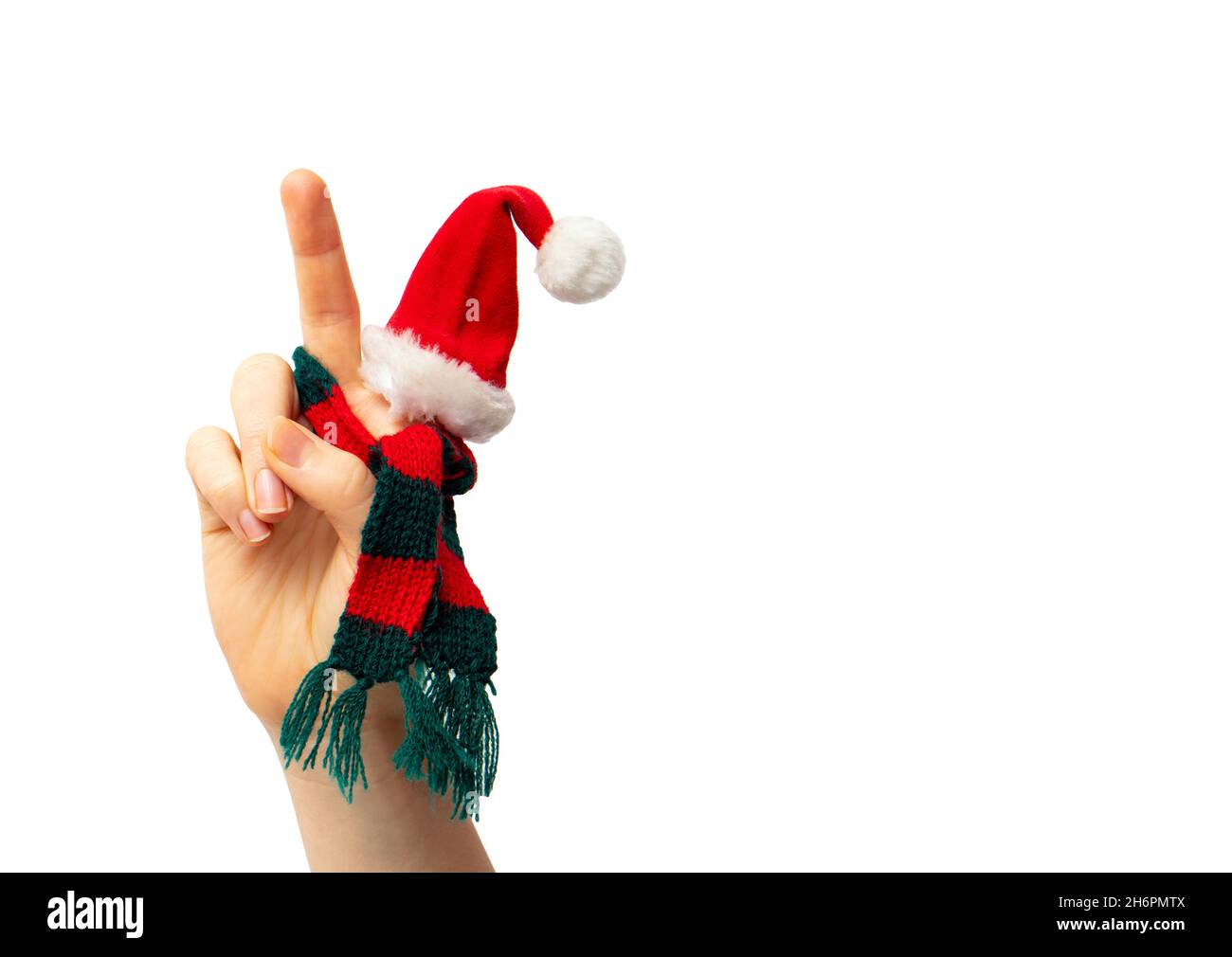 Close up view of isolated person hand show peace gesture, while wearing Christmas hat and knitted red and green scarf. Lot of copy space. Stock Photo