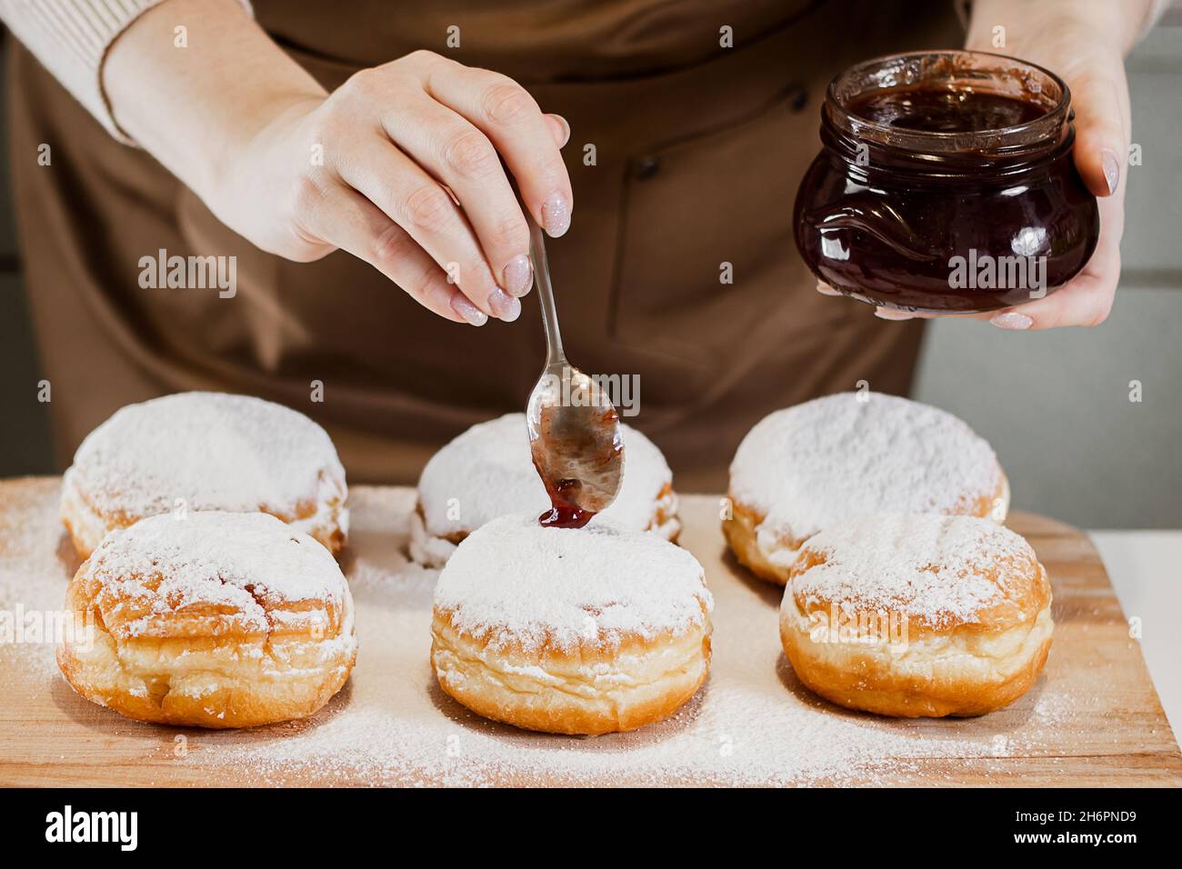Cooking traditional Hanukkah sufganiyot. A woman decorates donuts with