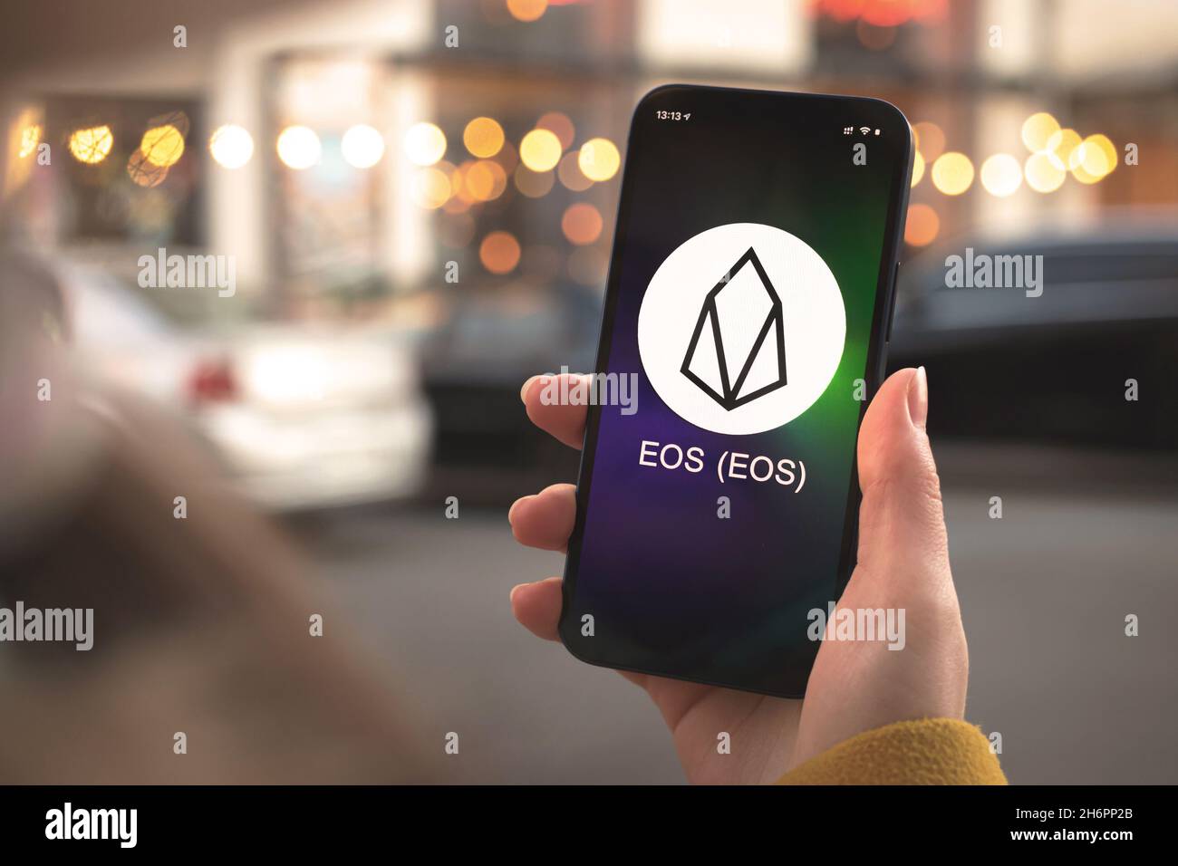 EOS cryptocurrency symbol, logo. Business and financial concept. Hand with smartphone, screen with crypto icon closeup Stock Photo