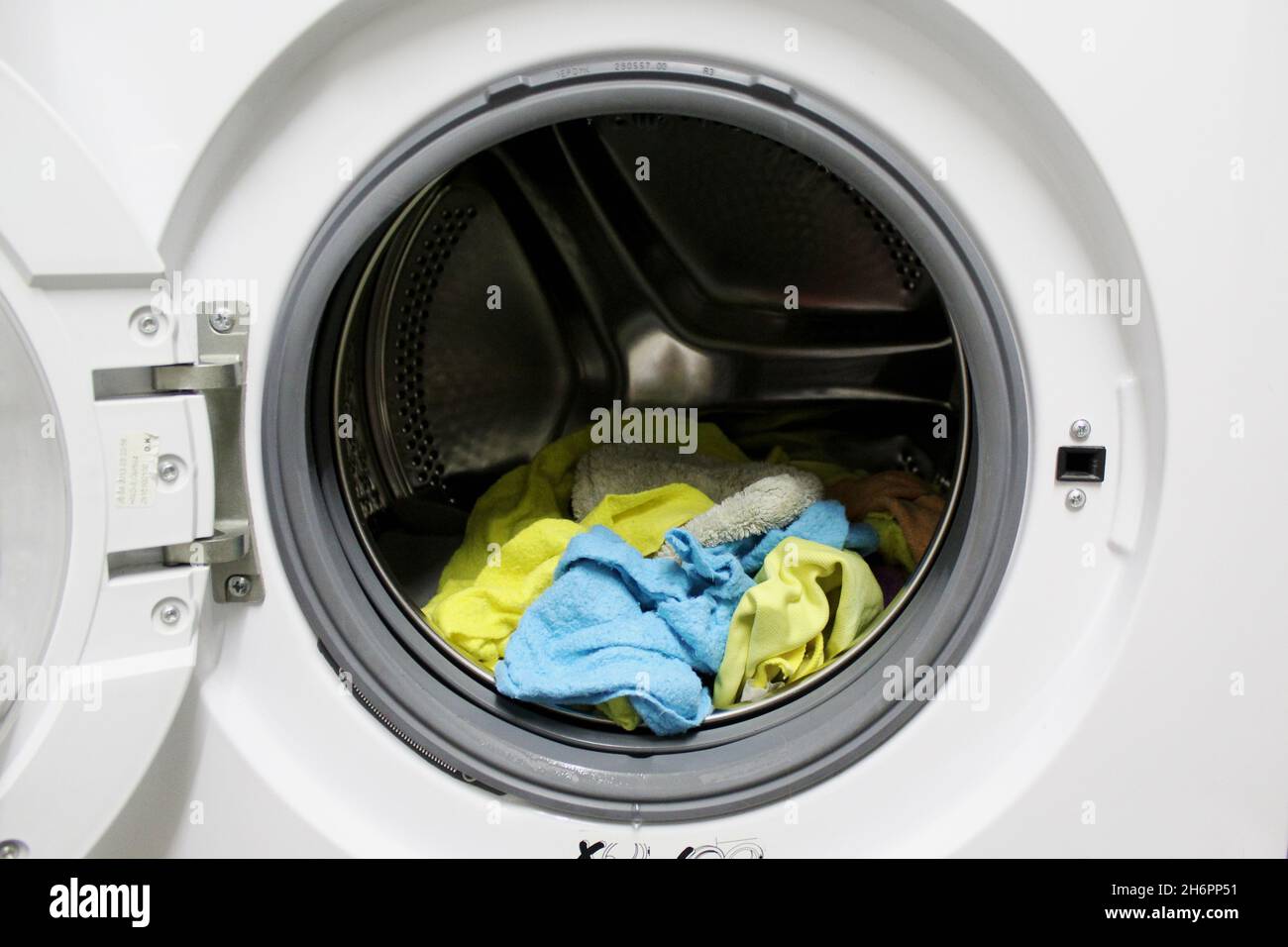 Gewaschene, saubere Putztücher in gelb und blau, die noch in der Waschtrommel der Waschmaschine liegen. Stock Photo