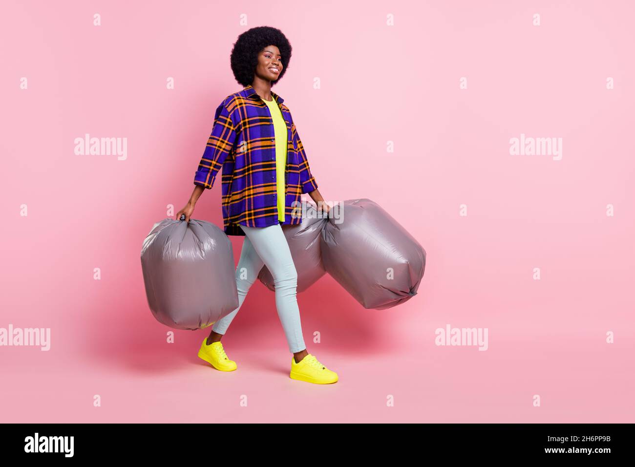 Full length body size view of attractive cheerful girl carrying trash bags isolated over pink pastel color background Stock Photo