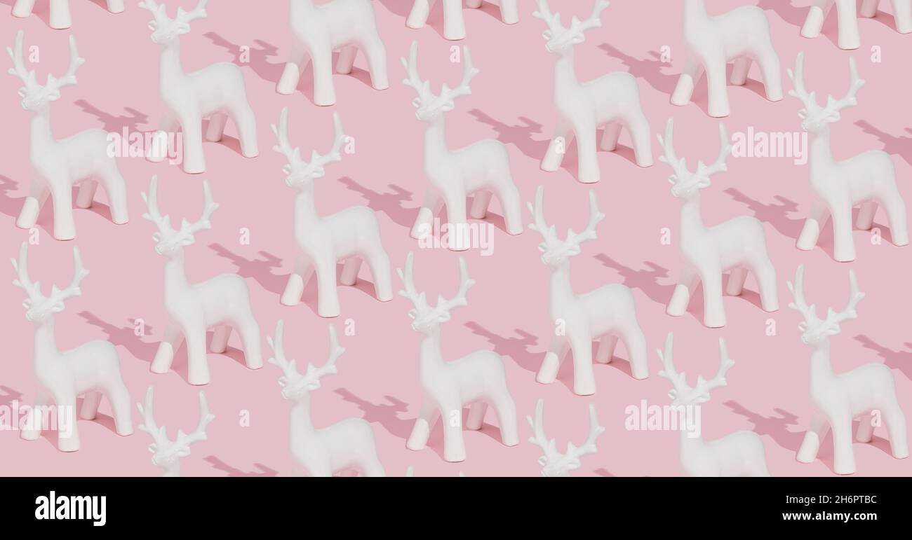 Creative pastel pink winter pattern made with white reindeer ornaments ...