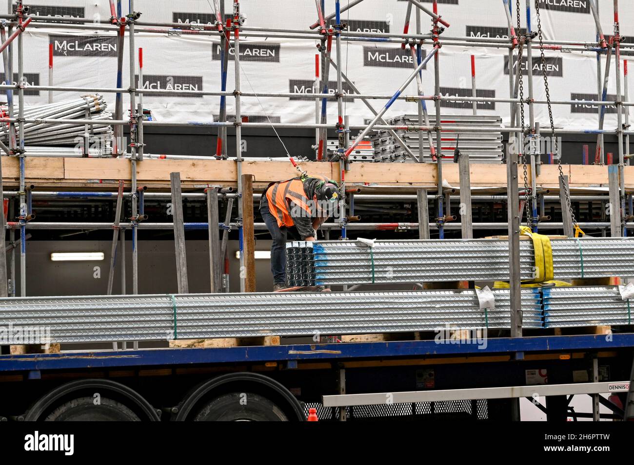 London, England - August 2021: Construction worker wearing safety harness preparing for a load of steel building materials to be lifted by crane Stock Photo