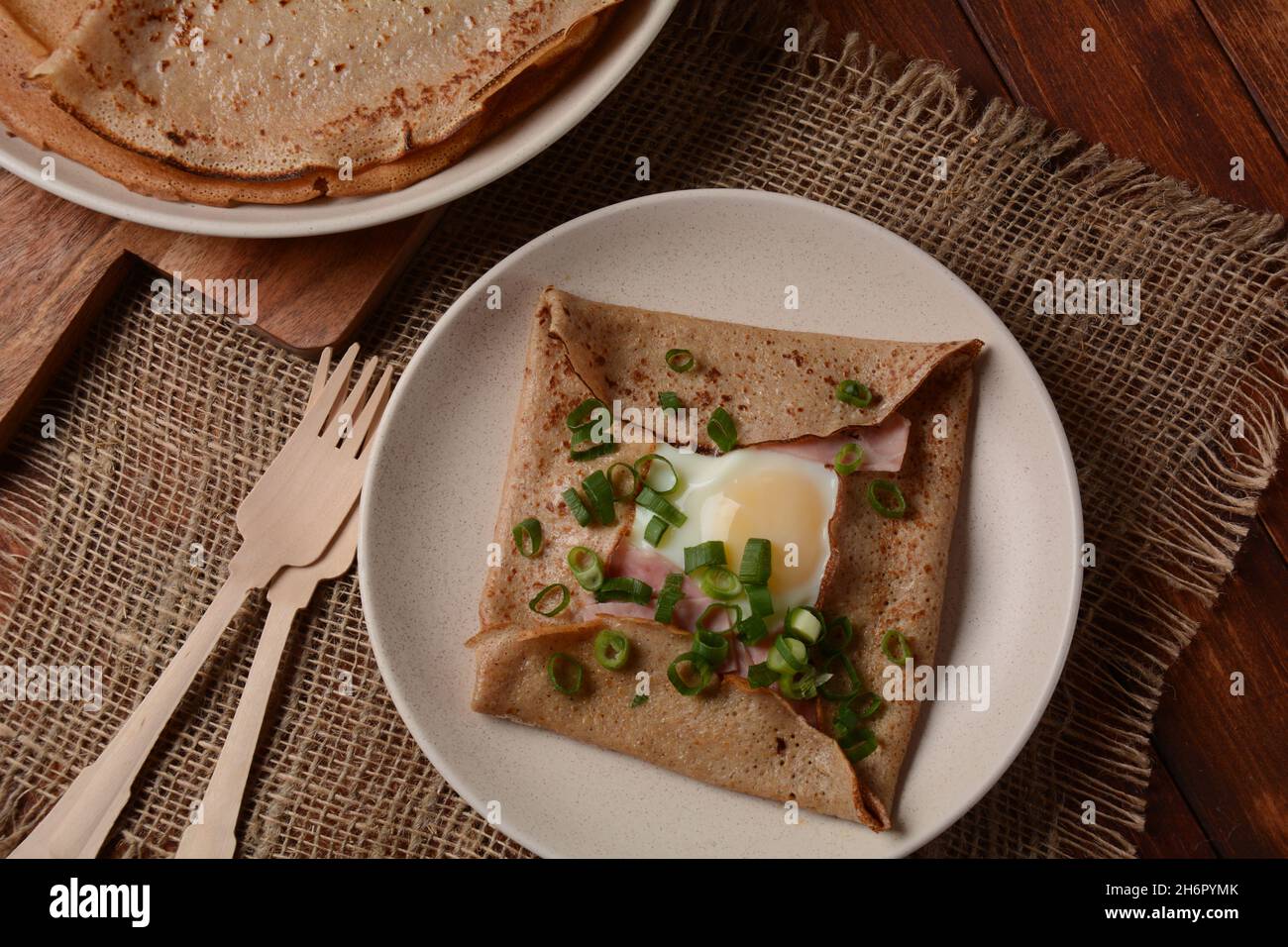 Breton galette, galette sarrasin, buckwheat crepe, with fried egg, cheese, ham. French Brittany cuisine. Stock Photo