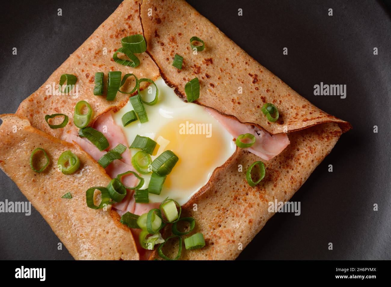 Breton galette, galette sarrasin, buckwheat crepe, with fried egg, cheese, ham. French Brittany cuisine. Stock Photo
