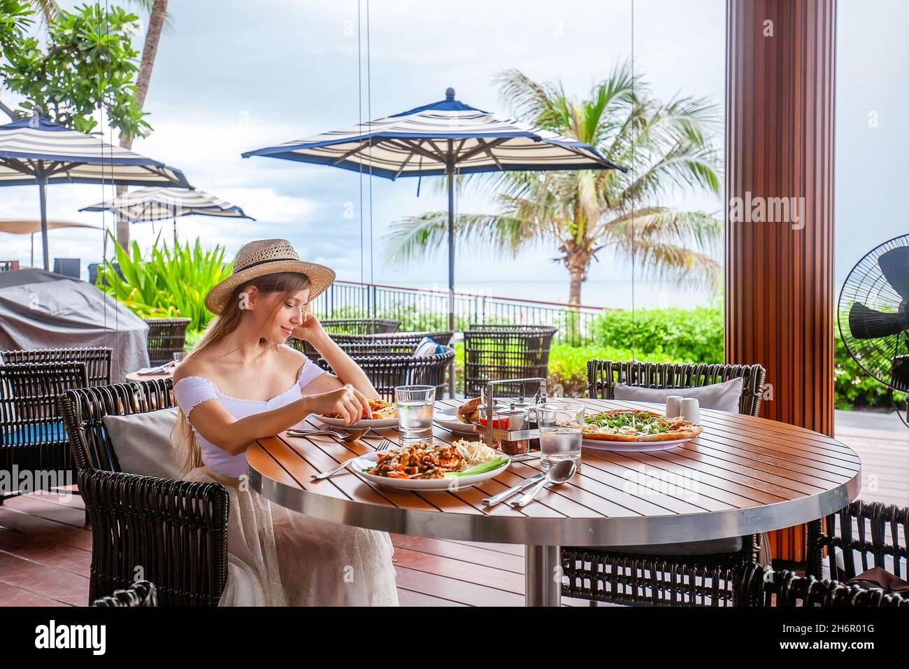 Attractive woman eats italian pasta in outdoor restaurant or cafe, prepared food Stock Photo