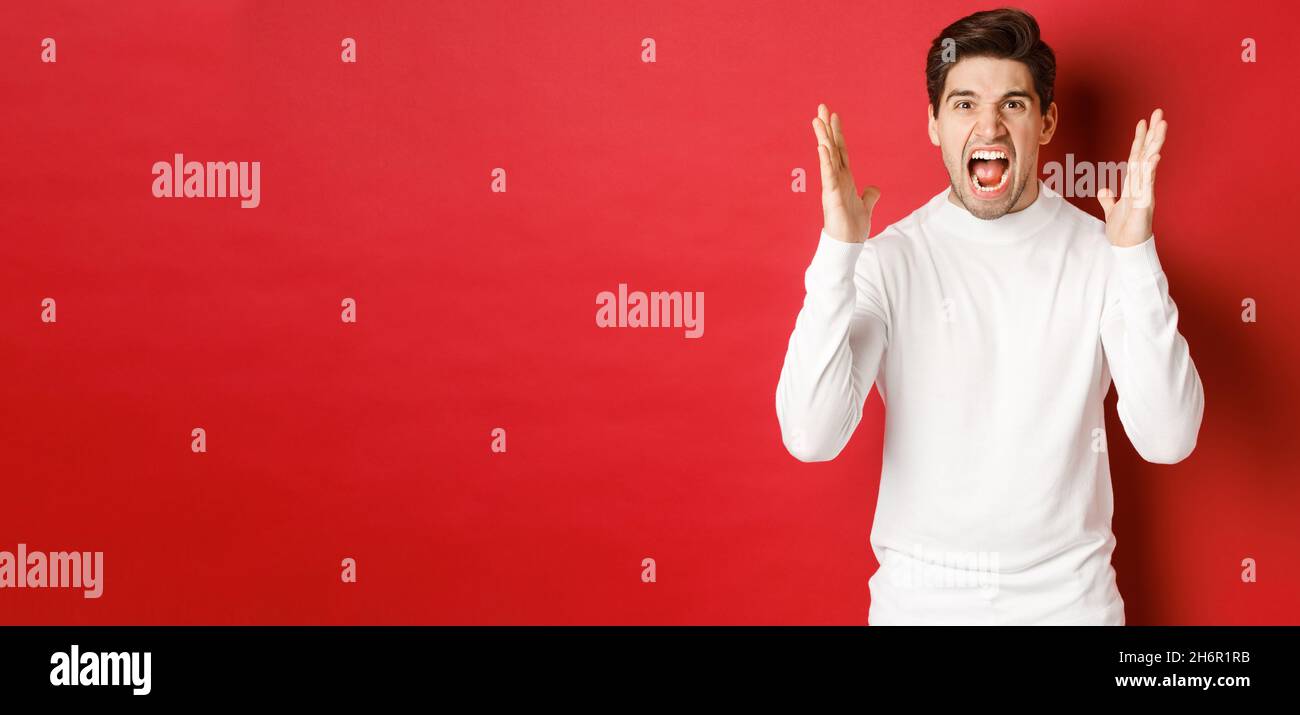 Image of frustrated and angry man in white sweater, shouting in rage ...