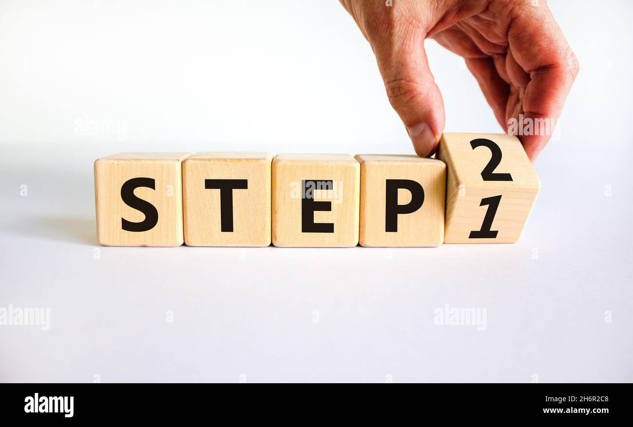 Step 1 or 2 symbol. Businessman turns a wooden cube and changes words ...
