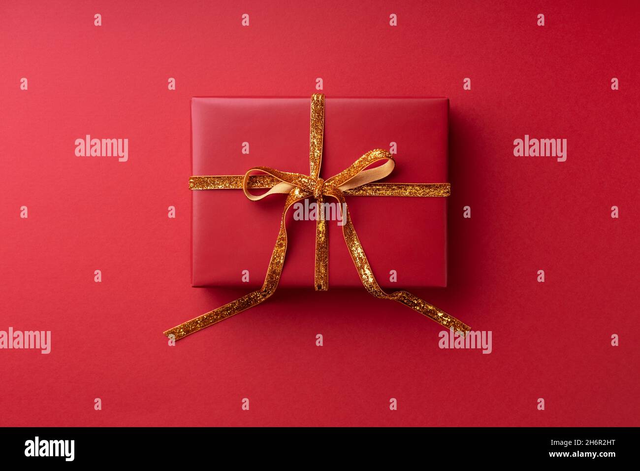 Red gift box tied golden ribbon on red background Stock Photo - Alamy