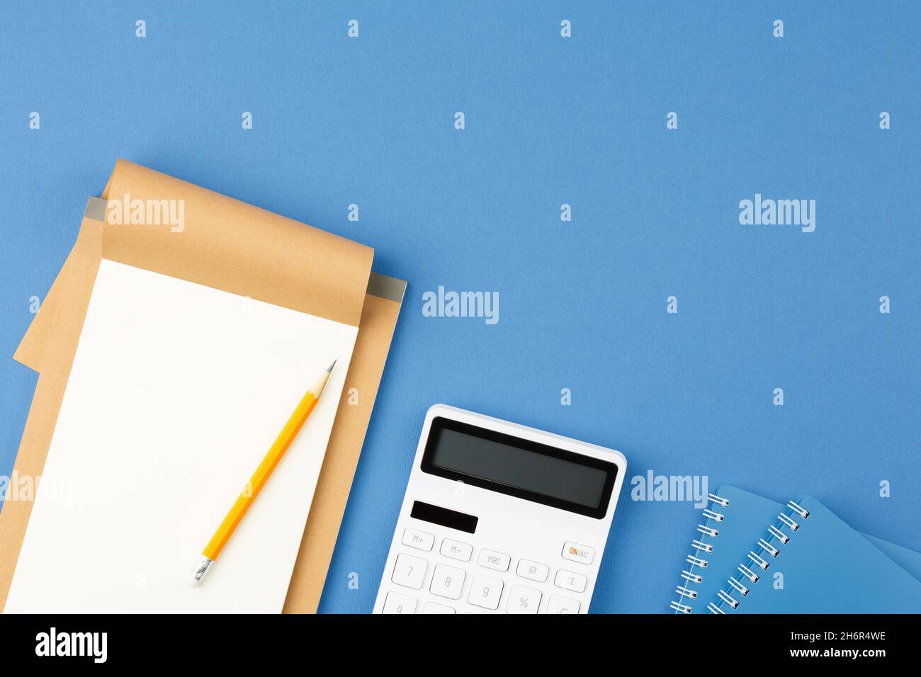Notepad, pencil and calculator on blue background. Stock Photo
