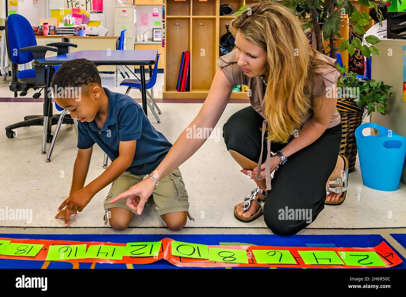 A pre-kindergarten teacher helps a student arrange numbers by twos, May 18, 2012, in Columbus, Mississippi. Stock Photo