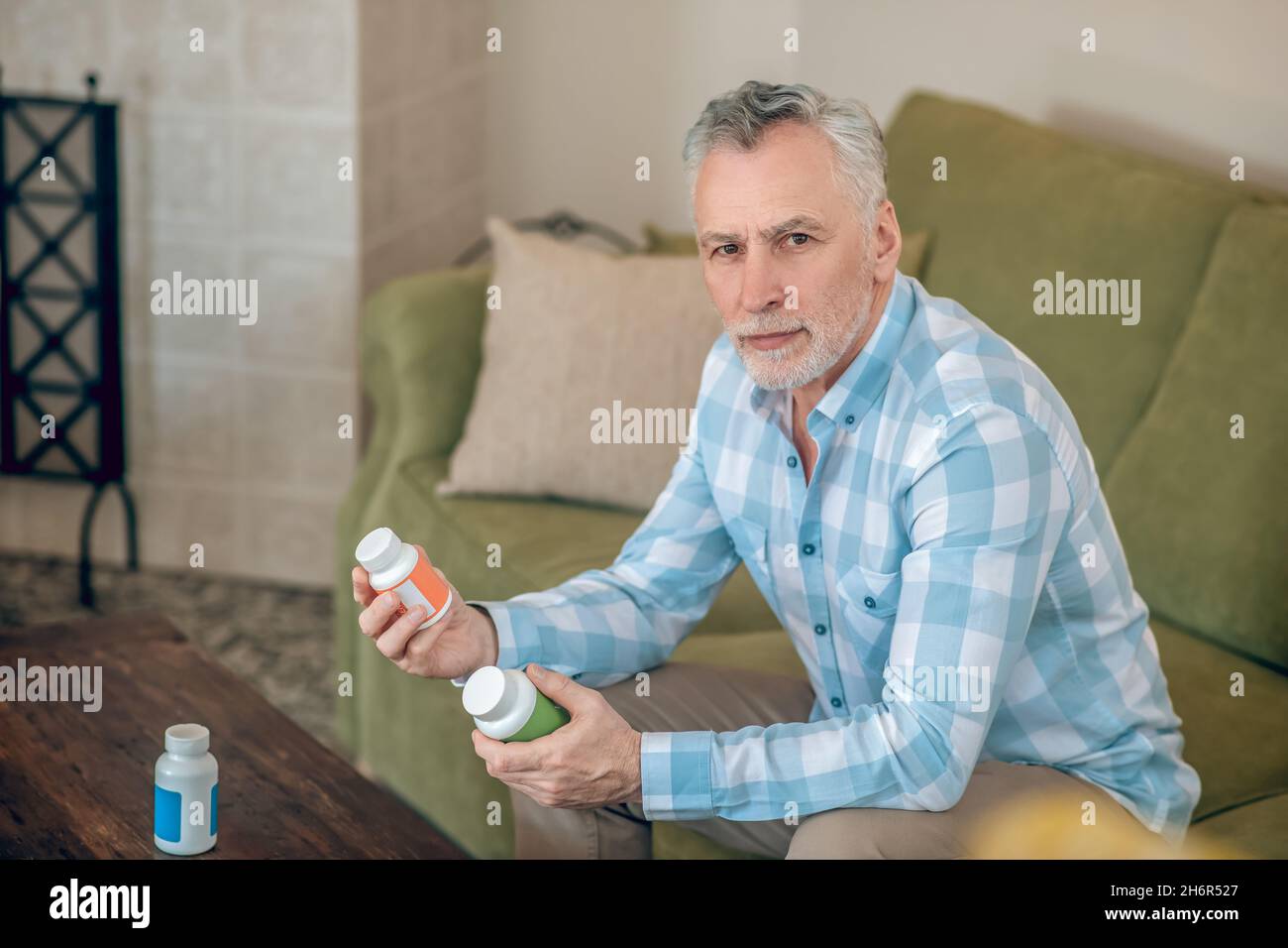 Man in a plaid shirt holding dietary supplements Stock Photo