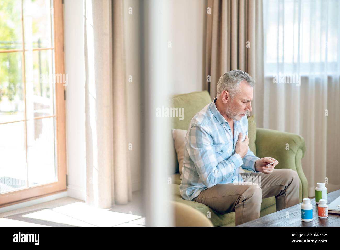 Male having a heart attack on the sofa Stock Photo