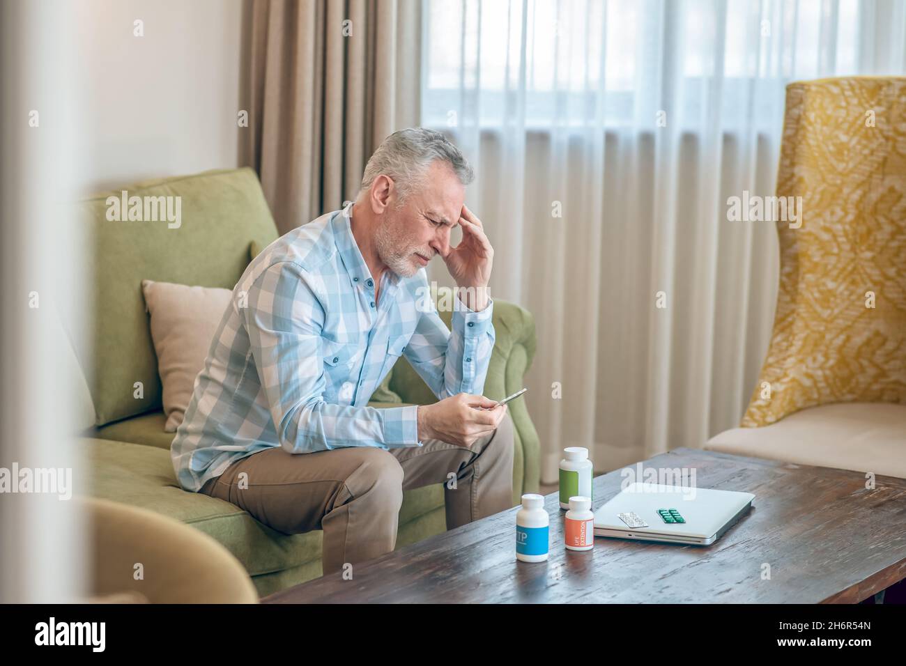 Gray-haired bearded mature man suffering from a headache Stock Photo