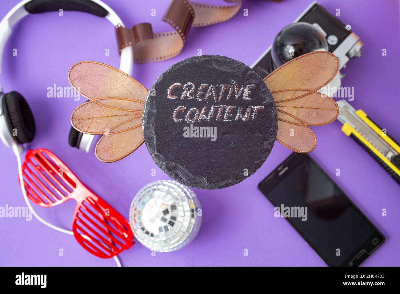 creative content written with chalk on a black stone tile, with different  objects blurred in the background Stock Photo