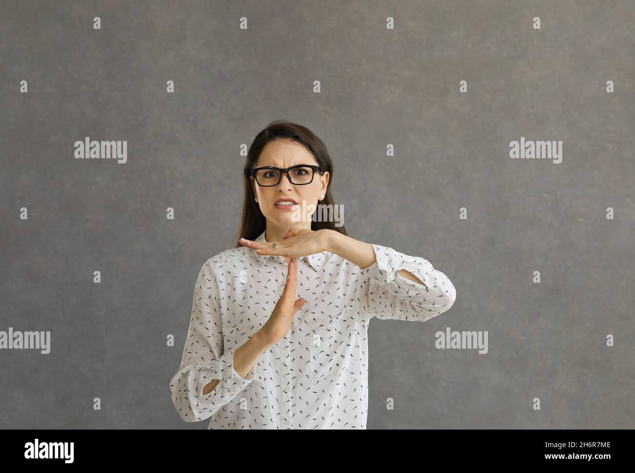 An annoyed young woman asking you to stop and doing a time out sign hand gesture Stock Photo