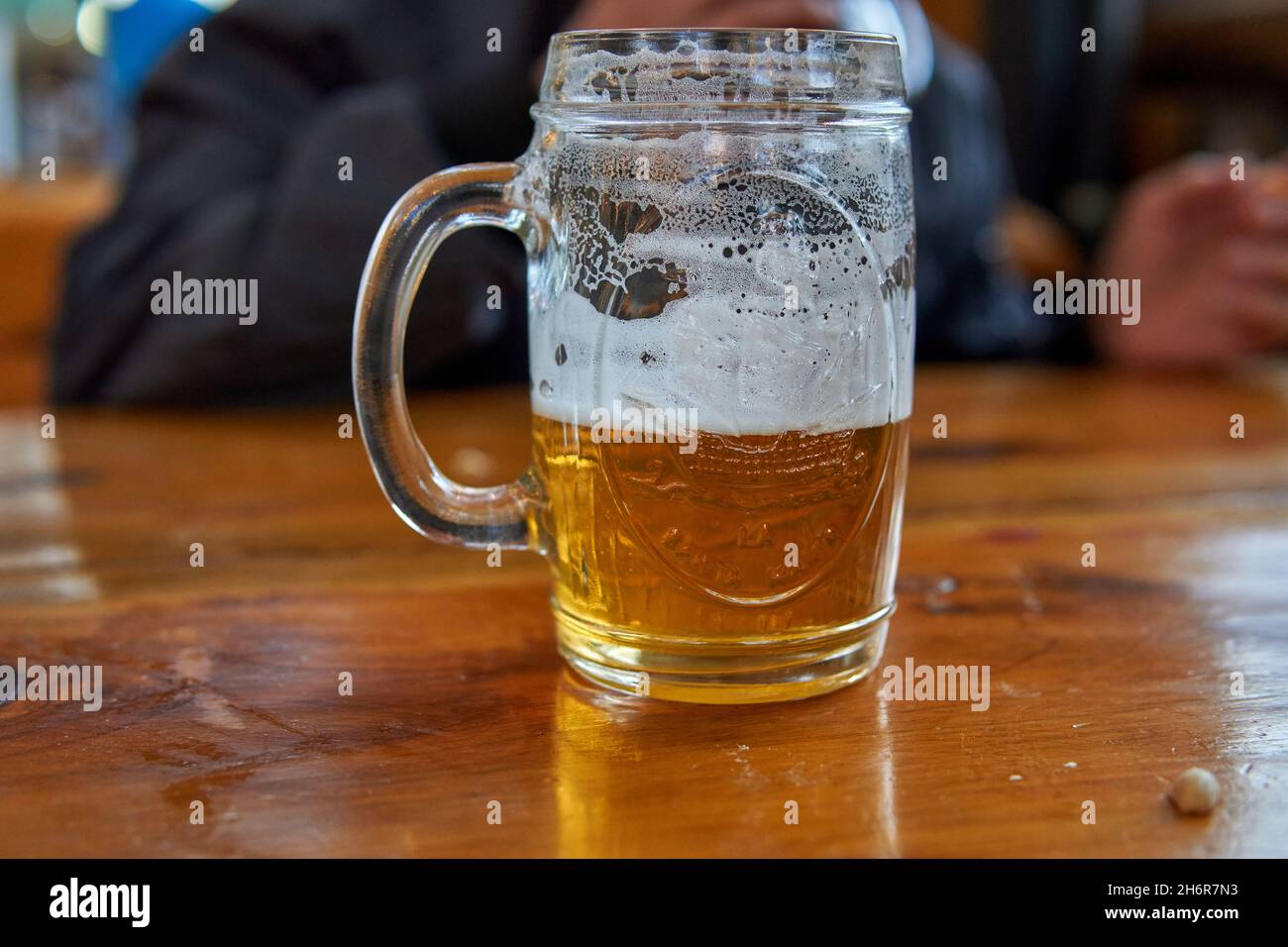 Isolated Cold honey craft beer with foam in a mug, on a wooden table. Horizontal. Blurred background Stock Photo