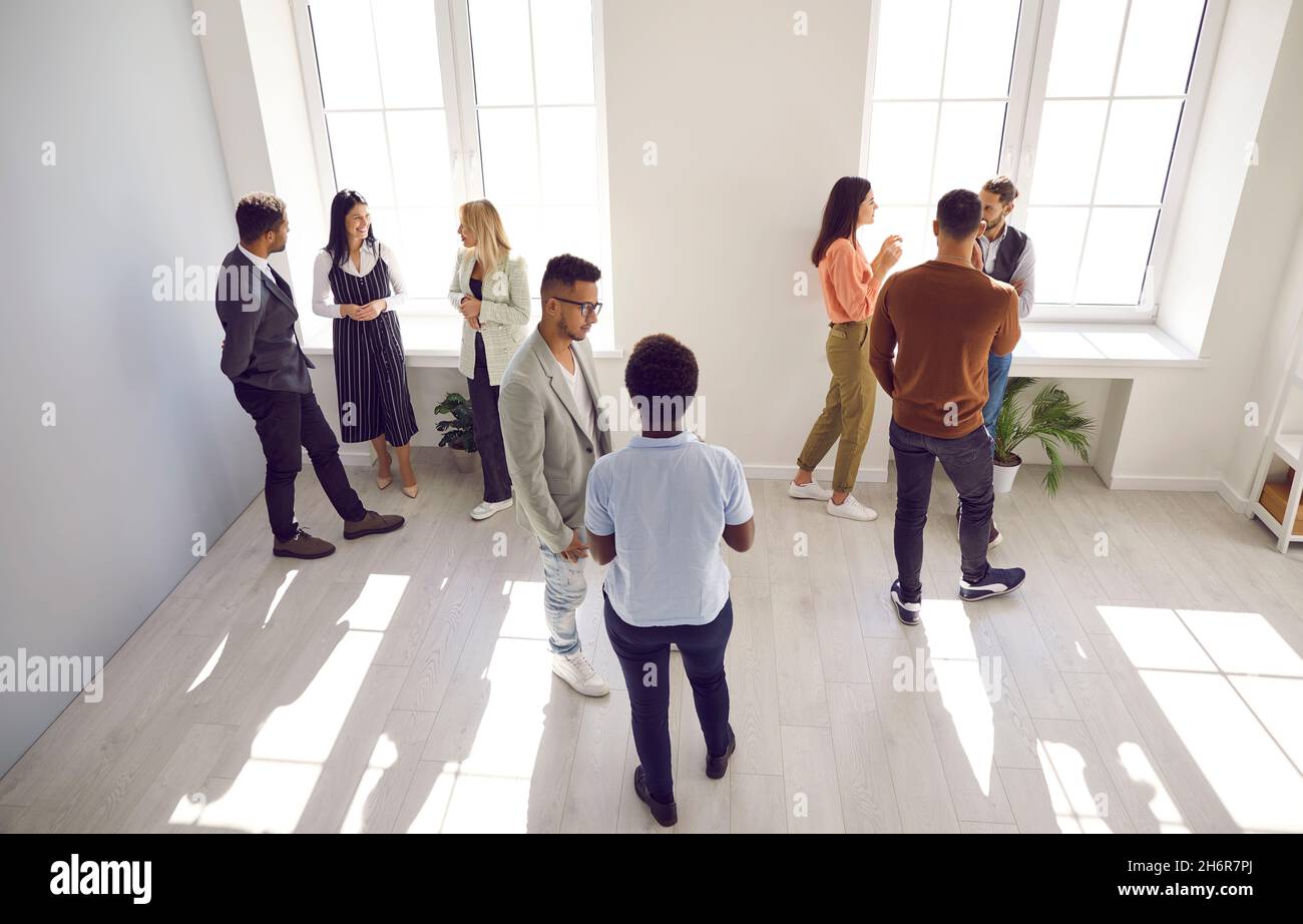 High angle shot of diverse people standing in office and discussing something in groups Stock Photo