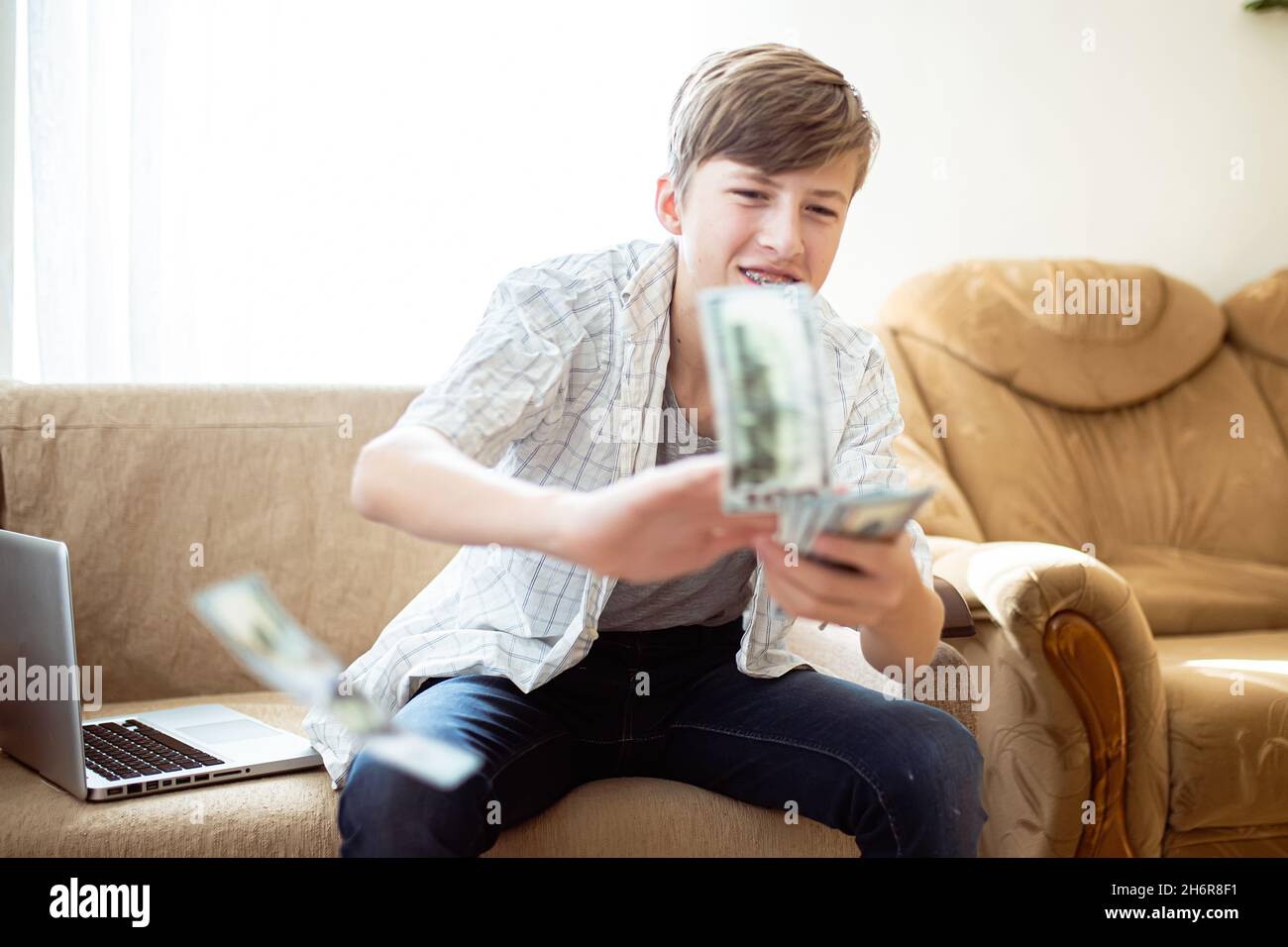 teenager wastes money. Boy happily scatters banknotes. Boy throwing