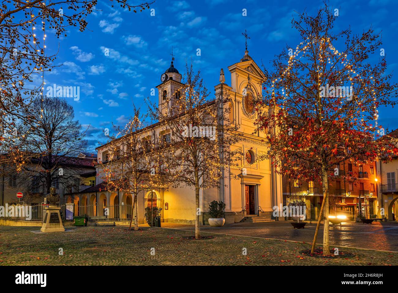 Catholic church on small town square in the evening surrounded by the trees with Christmas lights in Alba, Piedmont, Northern Italy. Stock Photo