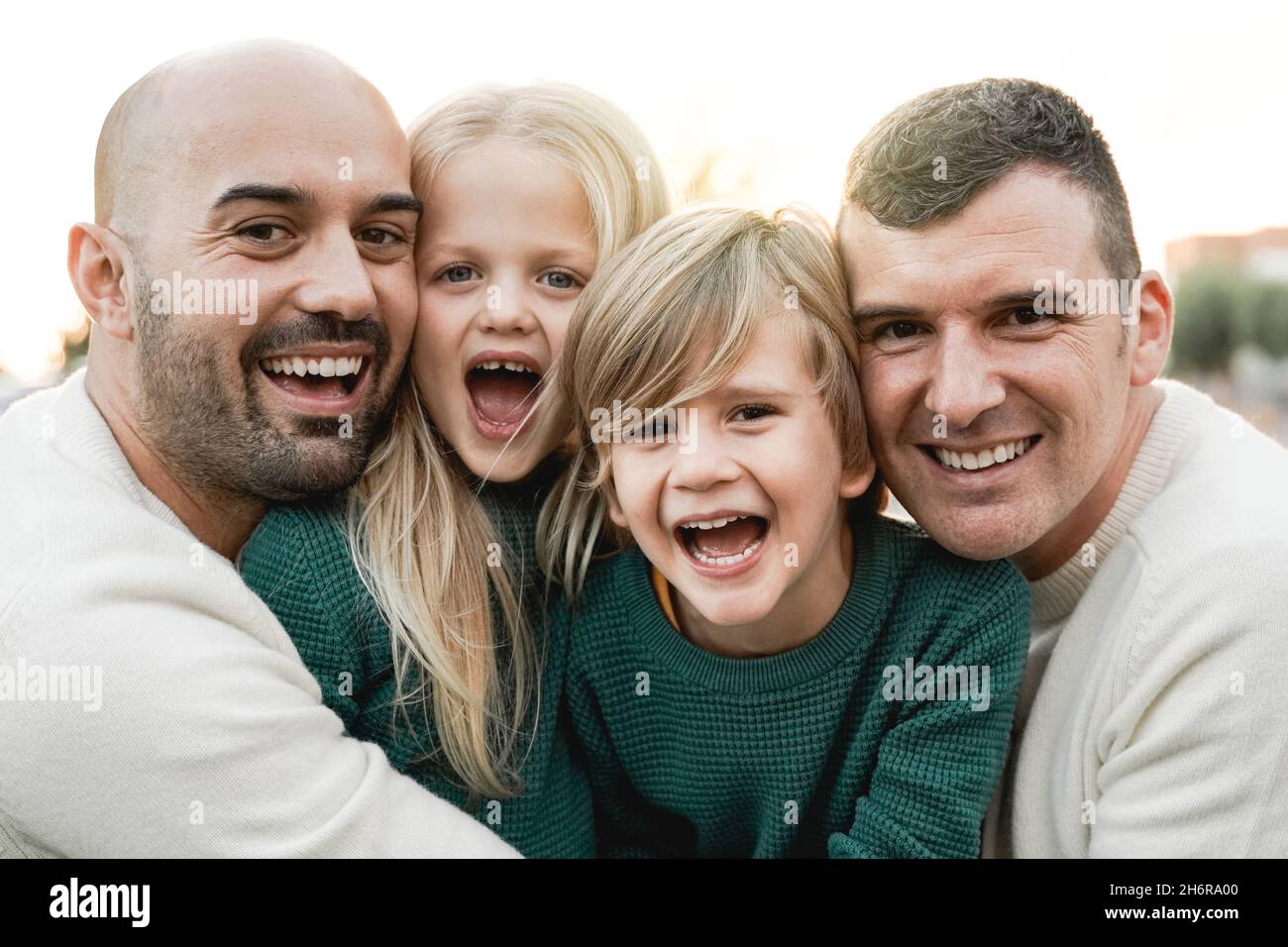 LGBT family outdoor - Happy gay men couple and sons having fun together at city park - Focus on center kid face Stock Photo