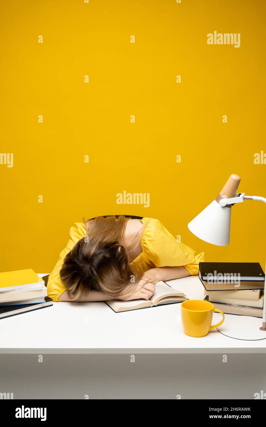 Tired student girl with glasses sleeping on the books in the library ...