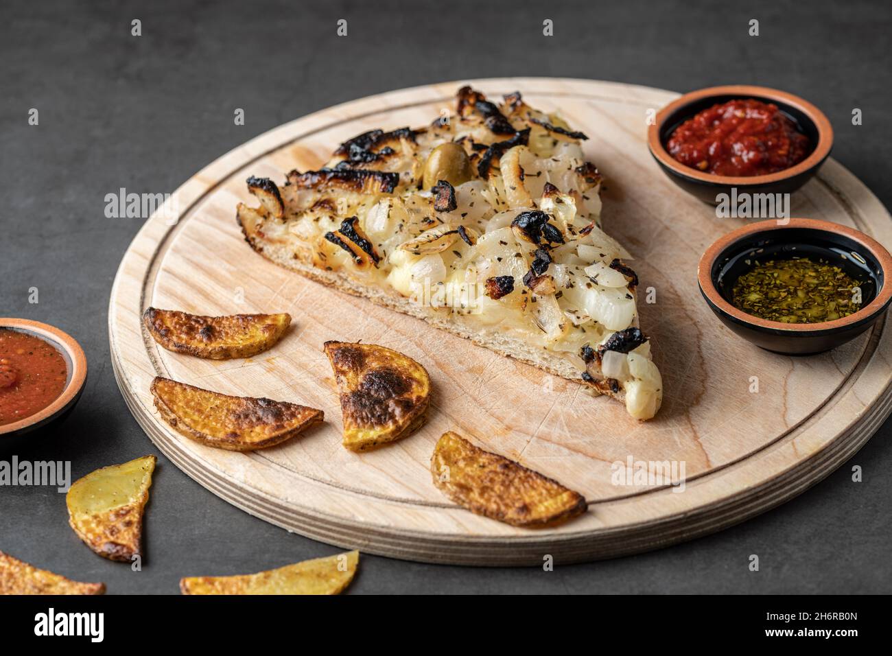 Handmade Argentinian pizza with onions on dark stone background. Stock Photo