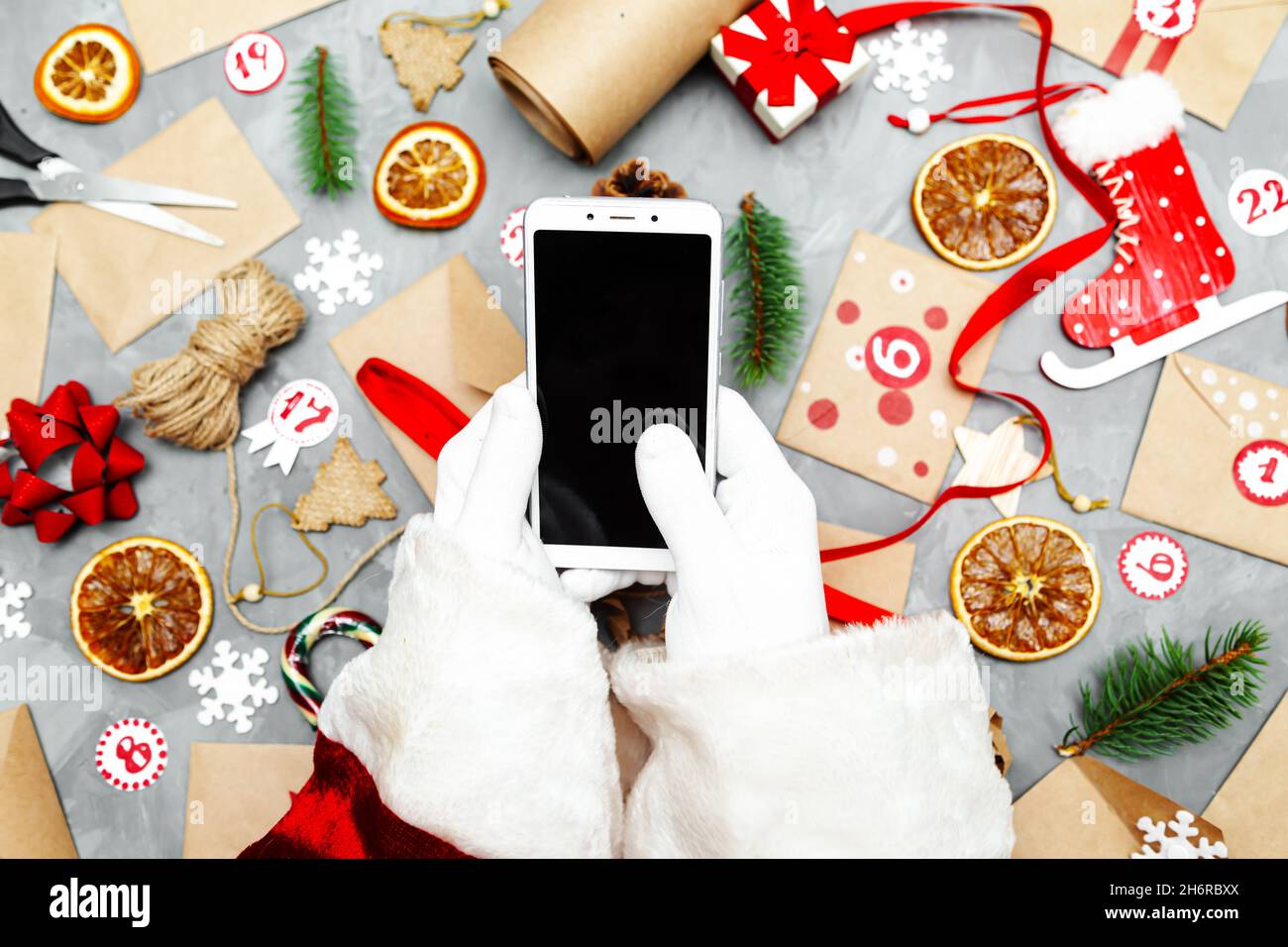 Hands of Santa Claus with a phone. Preparing the Advent Calendar.  Seasonal Christmas tradition. Flat lay, top view. Stock Photo