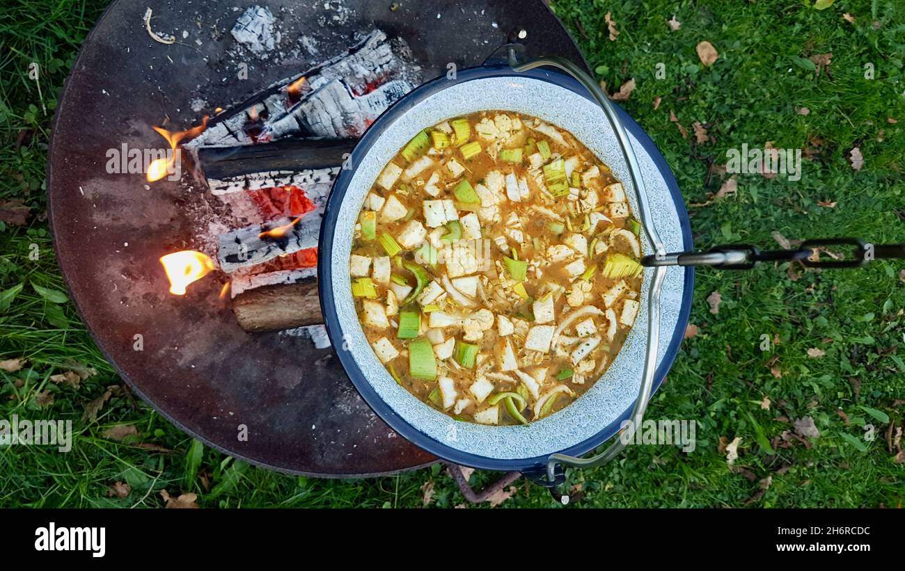 https://c8.alamy.com/comp/2H6RCDC/large-pot-over-a-fire-bowl-cooking-vegetable-soup-in-cast-iron-cauldron-outdoors-aerial-view-2H6RCDC.jpg