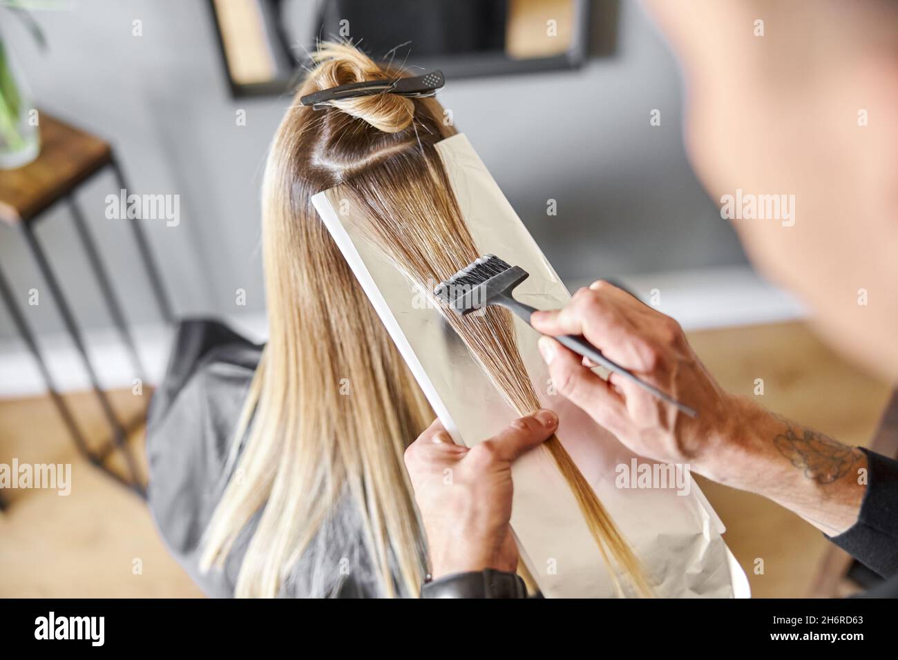 Confident male stylist is dyeing hair of blond caucasian female client Stock Photo