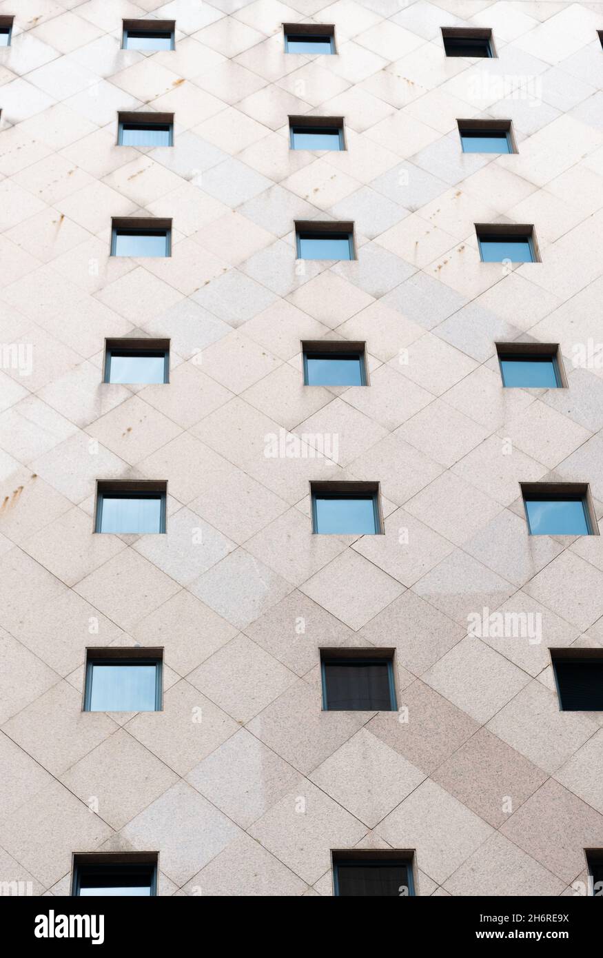 Part of the facade of a building with 12 windows in its concrete facade symmetrically placed in 4 rows and 3 columns, in the center of the city. Urban Stock Photo