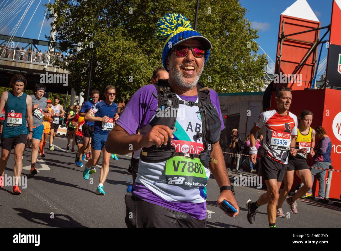 Smiling man Man in woolly hat running, Virgin Money London Marathon 2021 at the 25 mile point, Victoria Embankment. Stock Photo