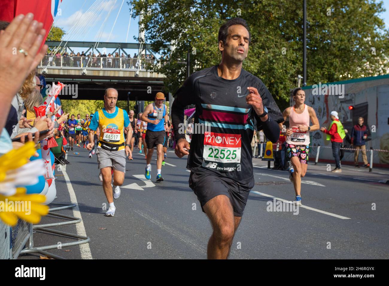 Man running with spectators clapping, Virgin Money London Marathon 2021 at the 25 mile point, Victoria Embankment. Stock Photo