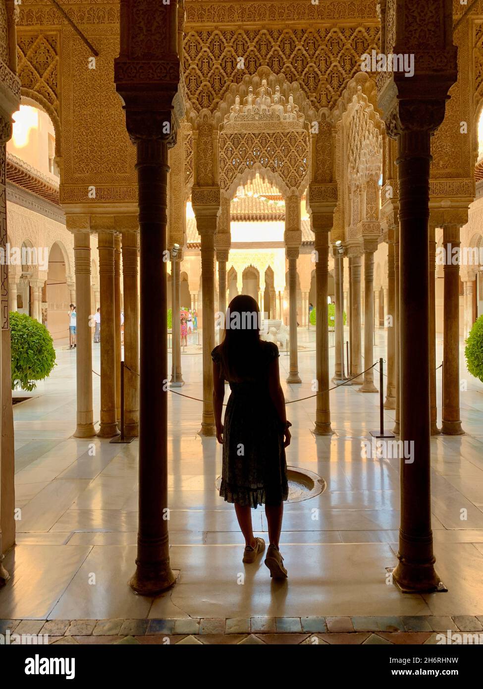 Brunette girl with long hair walking through the Nasrid Palaces of the Alhambra in Granada, under a beautiful and soft natural light creating beautifu Stock Photo