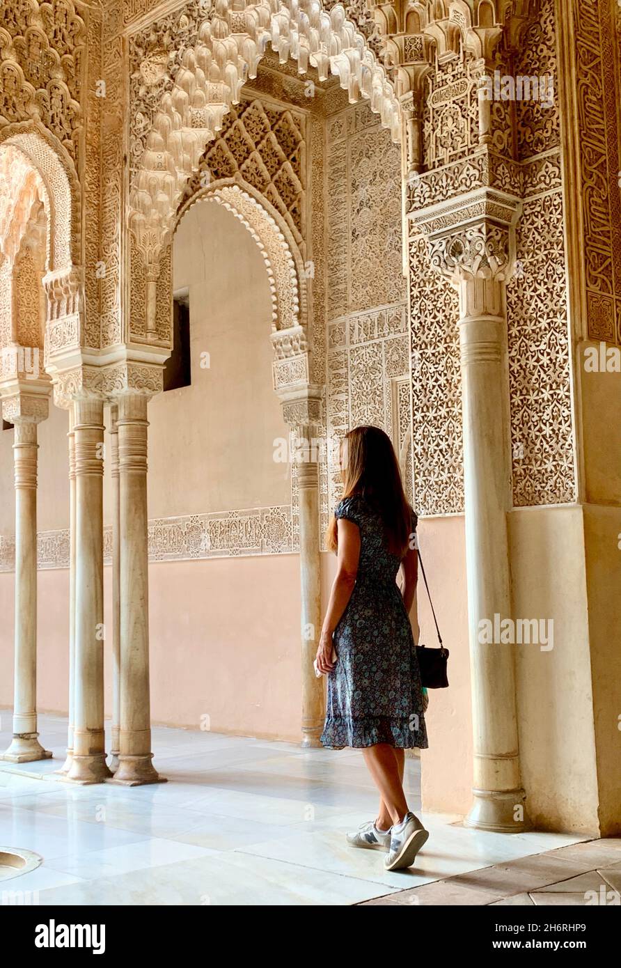 Brunette girl with long hair walking through the Nasrid Palaces of the Alhambra in Granada, under a beautiful and soft natural light creating beautifu Stock Photo
