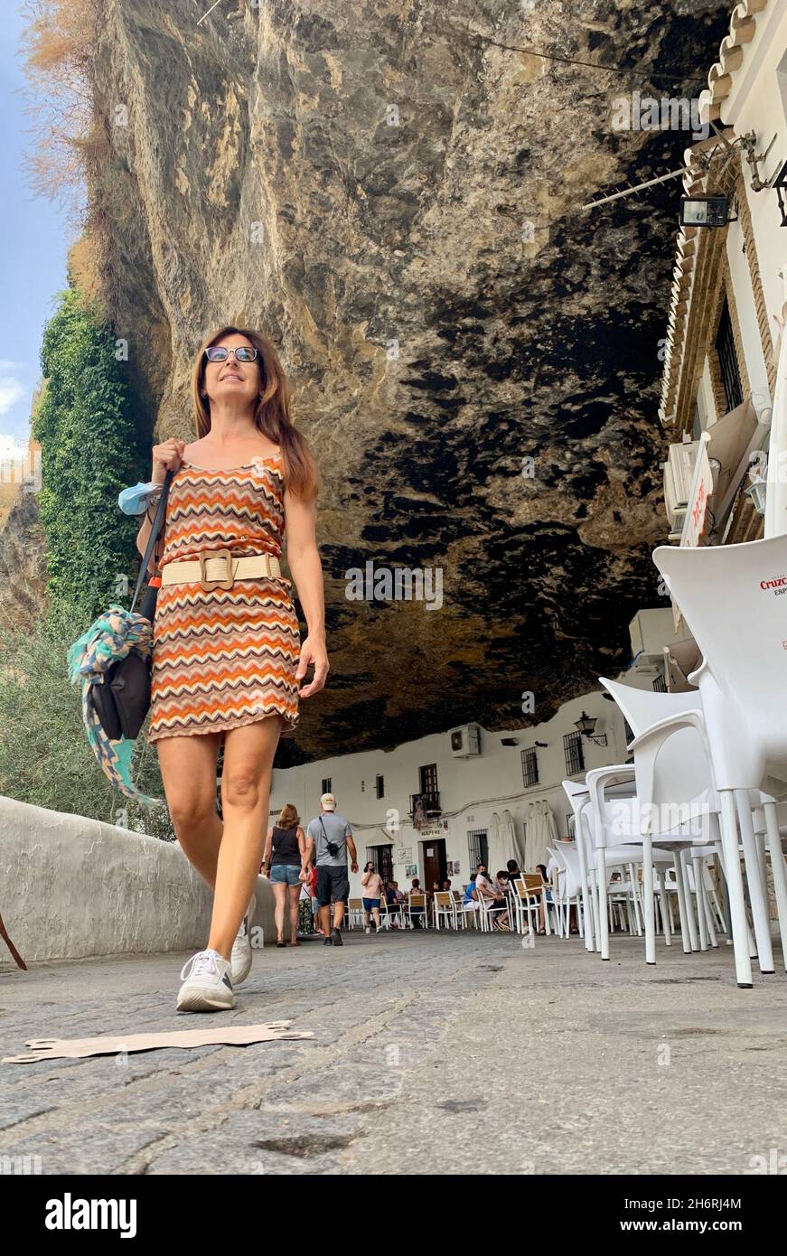 Girl with summer dress walking through the pretty streets of Setenil de las Bodegas, one of the famous white villages of Cadiz, Andalucia, Spain Stock Photo