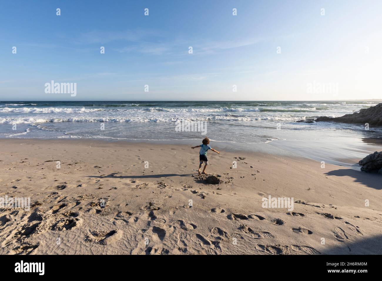 Young boy running in open space on a beach on the Atlantic coast. Stock Photo