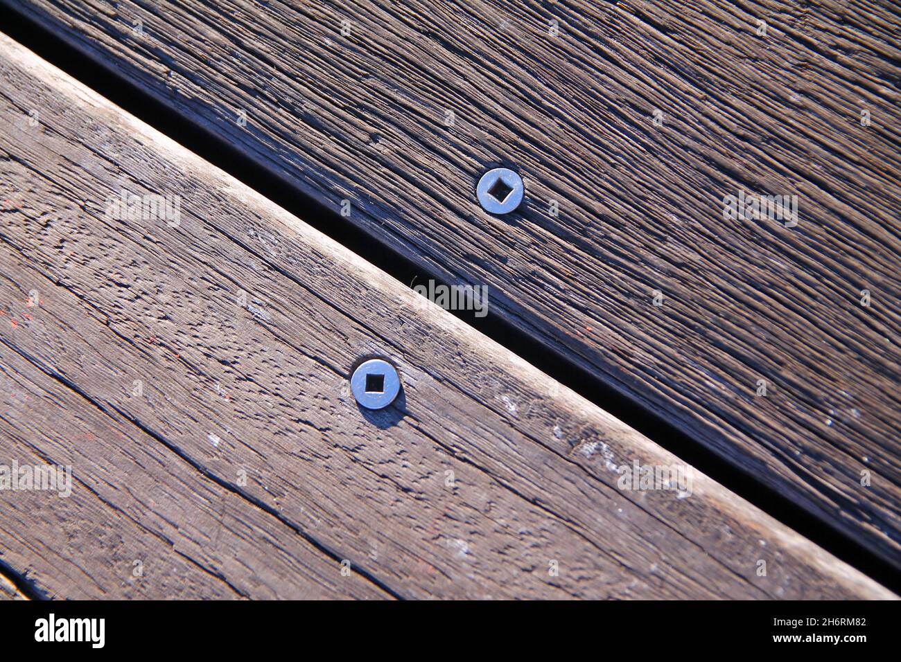Screws and nails on two wood steps of different trees on the boardwalk