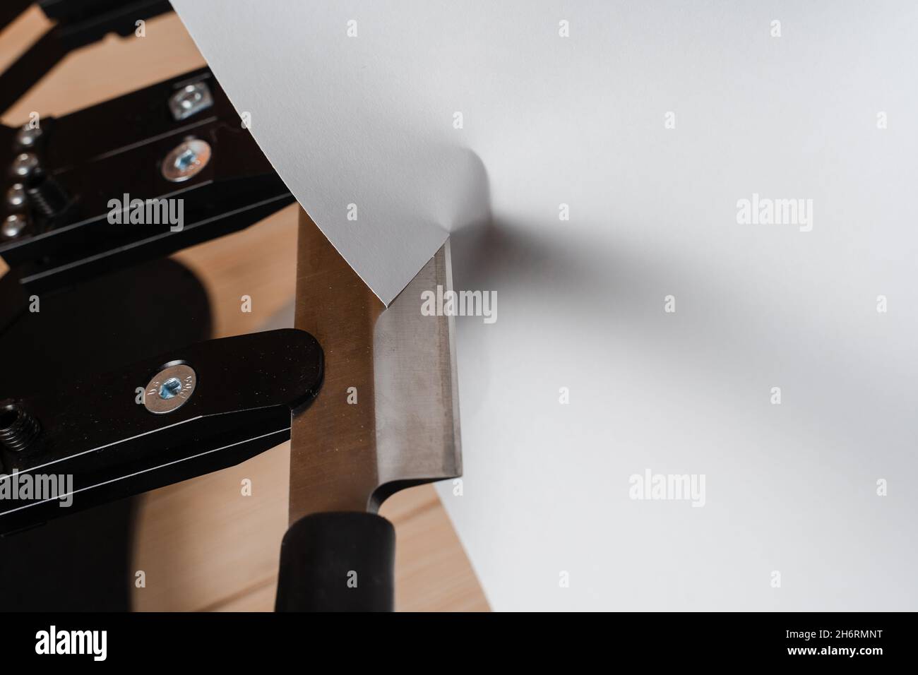 Process of cutting paper with a sharp knife near professional knife sharpener and a set of