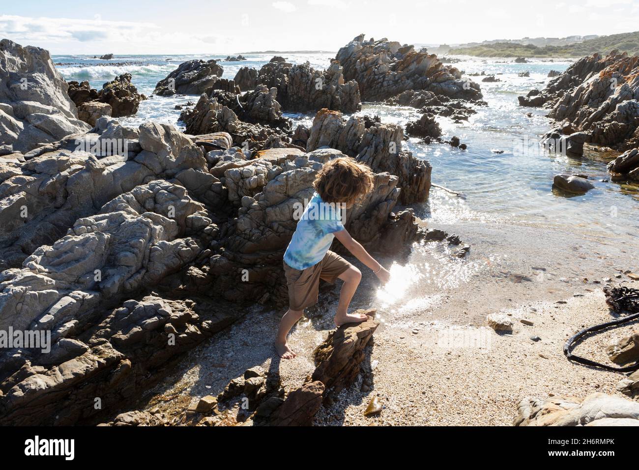 Eight year old boy exploring a rocky beach Stock Photo