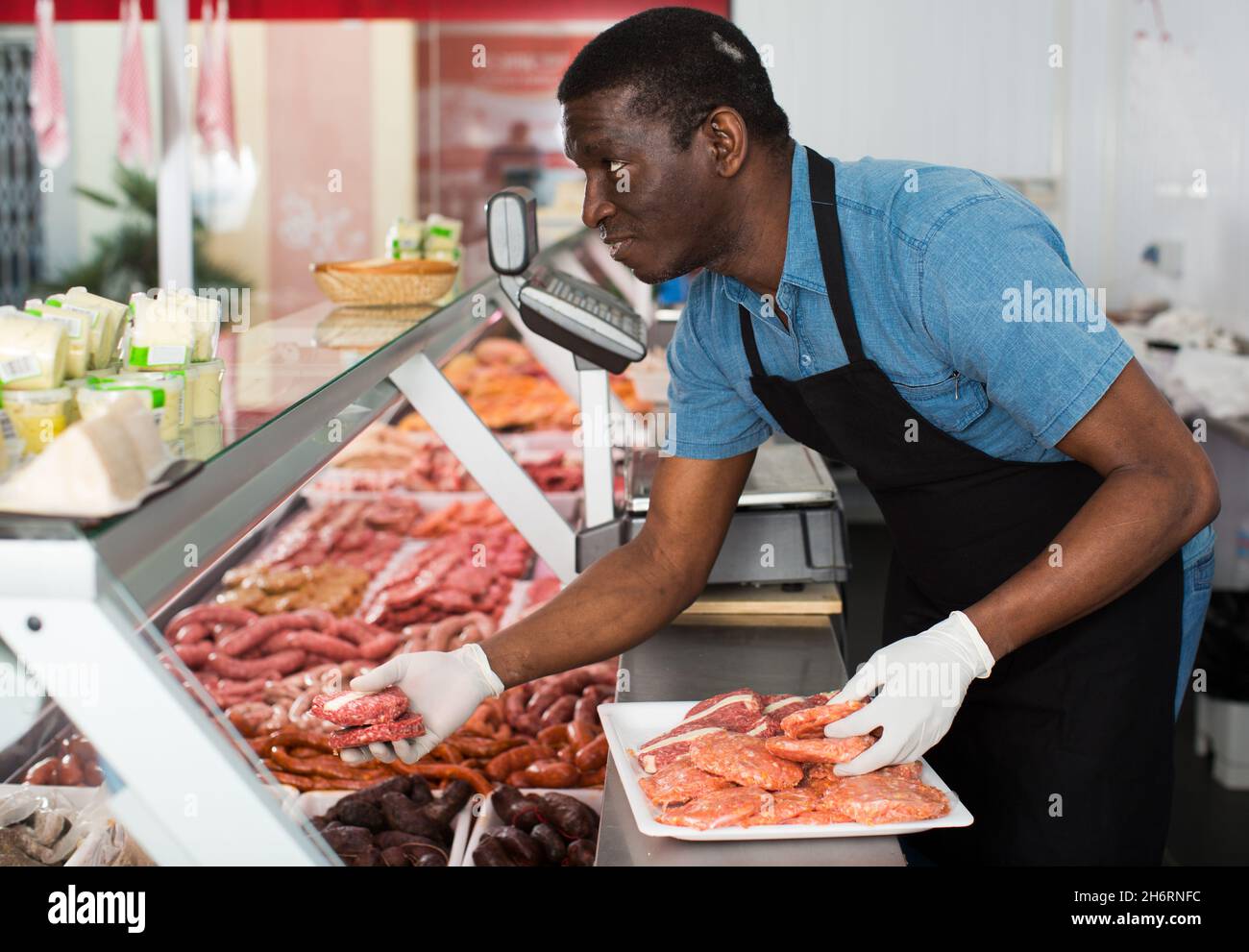 Butcher arranging meat display Stock Photo - Alamy