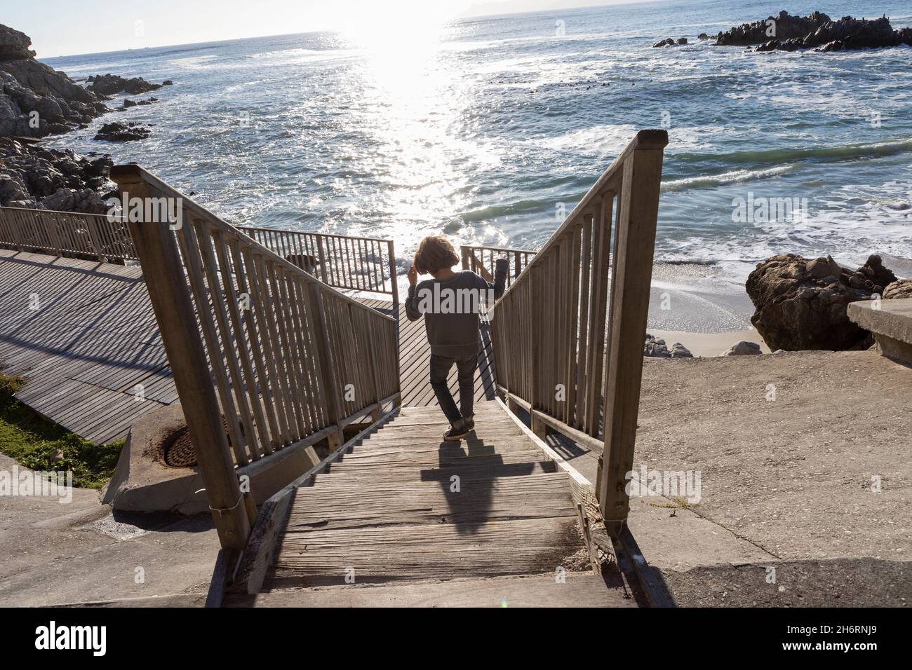 A boy running towards the beach down a set of steps Stock Photo