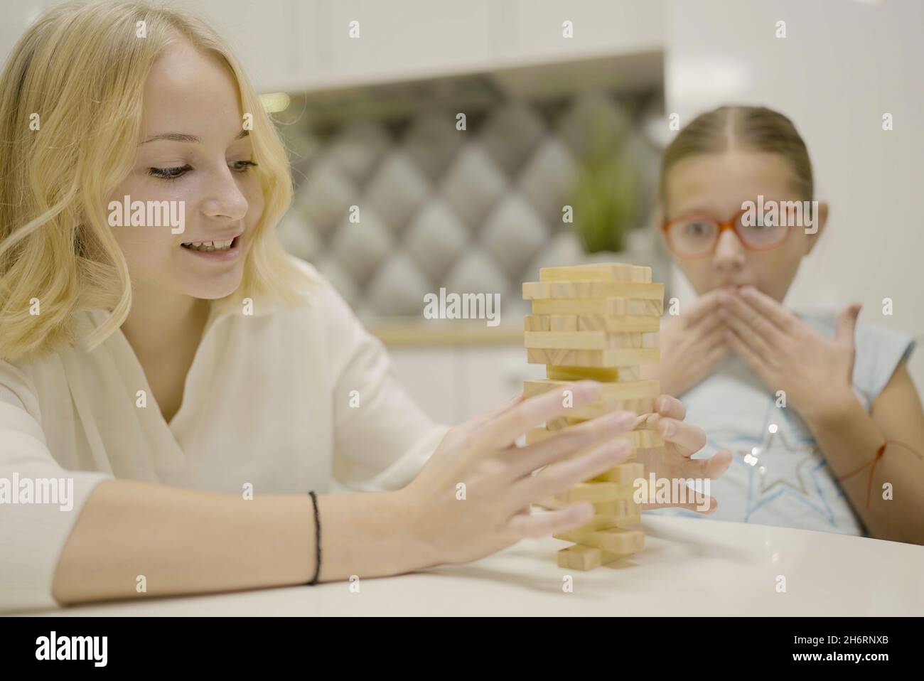 two girls have fun playing Jenga together board game to remove wooden