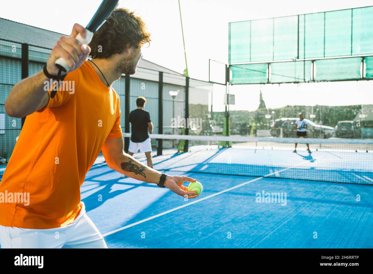 Mixed padel match in a blue grass padel court -  Beautiful girl and handsome man playing padel outdoor Stock Photo