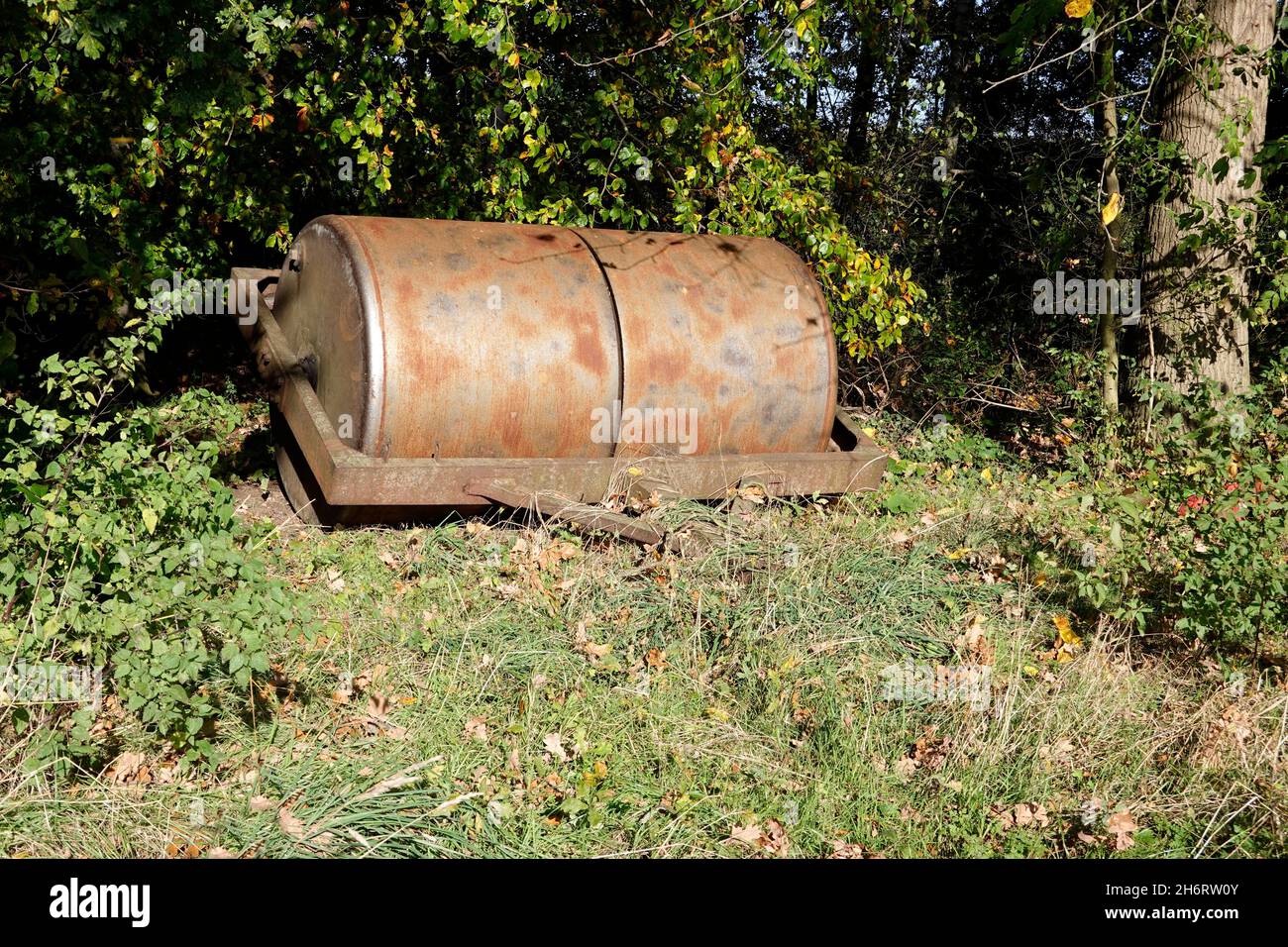 schwere, landwirtschaftlich genutzte Eisenwalze, abgestellt am Waldrand, Niedersachsen, Deutschland, Oetzen Stock Photo