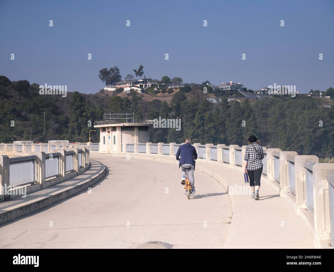 Los Angeles, CA, USA - November17, 2021: A bicyclist and a pedestrian cross Lake Hollywood via the Mulholland dam in Los Angeles, CA. Stock Photo